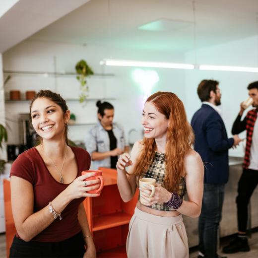 Zwei Frauen Unterhalten sich lachend mit einer Tasse Kaffee in der Hand