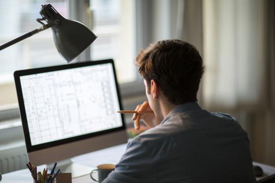 Ein dunkelhaariger Mann sitzt vor einem Computerbildschirm, auf dem Daten angezeigt werden