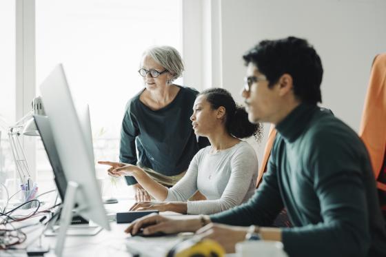 Drei Personen schauen gemeinsam auf einen Computerbildschirm.