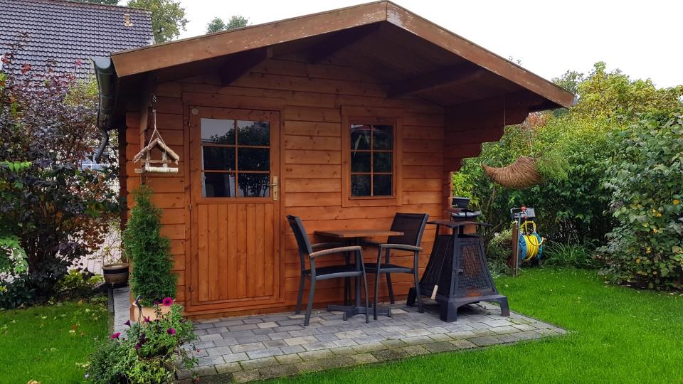 Holzgartenhaus von vorne in einem Garten.