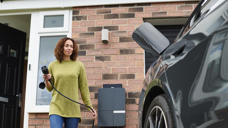 Hausbesitzer lädt ein Elektroauto auf in der Einfahrt.