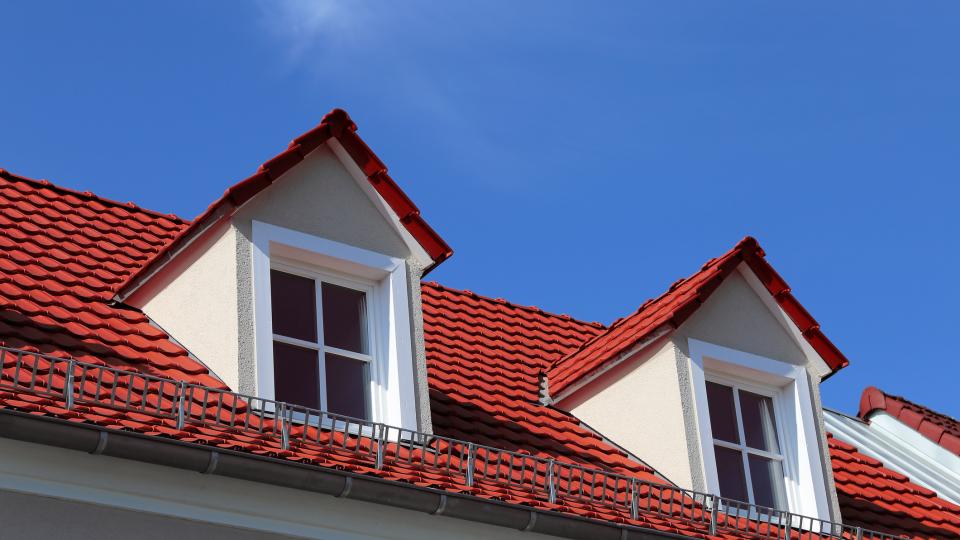 Zwei Dachgauben auf einem roten Dach.